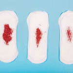 tres-toallas-sanitarias-con-brillantina-roja-simulando-diferentes-flujos-de-menstruación